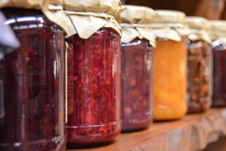 Amish Canning Blog Photo September 2023 Canning jars lined up on a wooden shelf filled with various Jellies and Jams